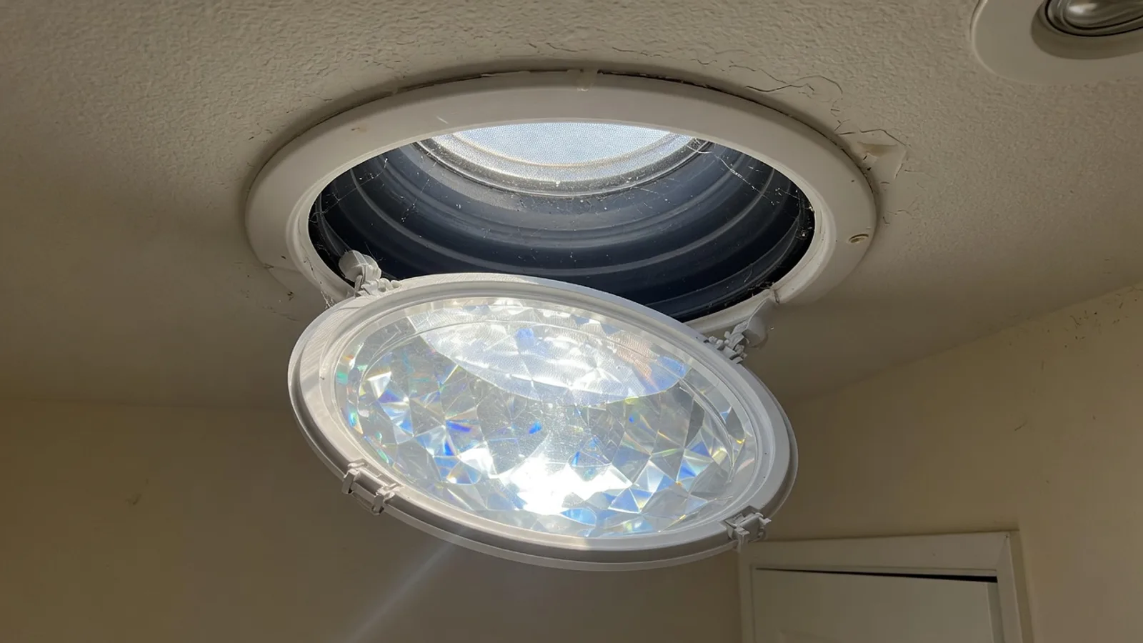 Round solar-tube diffuser in an Austin hallway ceiling