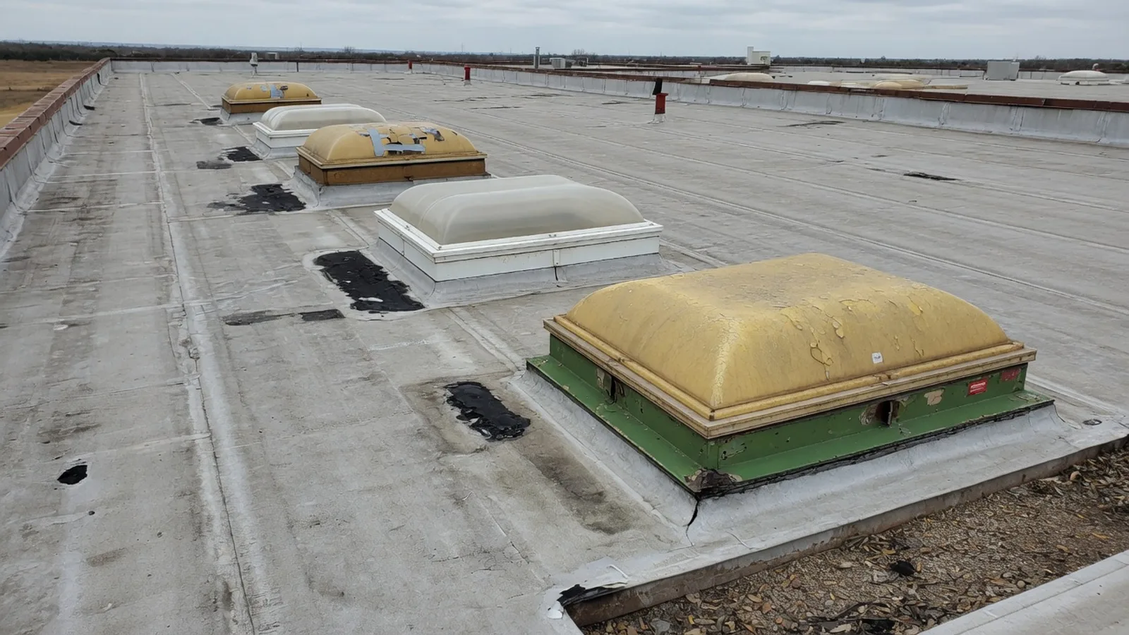 Aged curb-mounted skylights on a weathered Central Texas warehouse roof